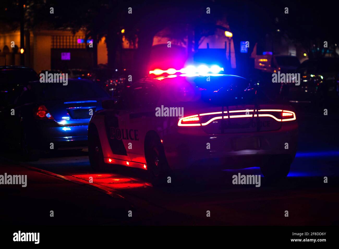 Police car with emergency lights flashing at night in city from the back Stock Photo