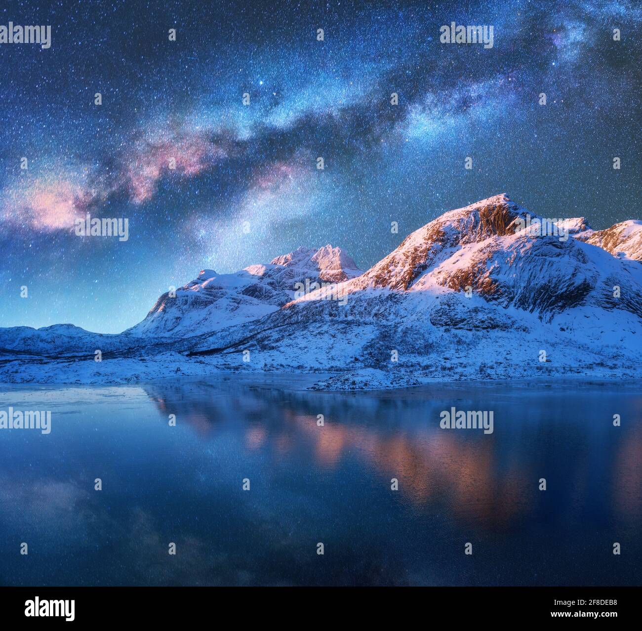 Milky Way above frozen sea coast and snow covered mountains in winter