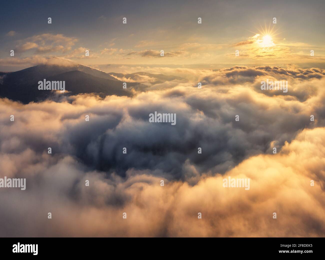Mountains in clouds at sunrise in summer. Aerial view of mountain peak ...