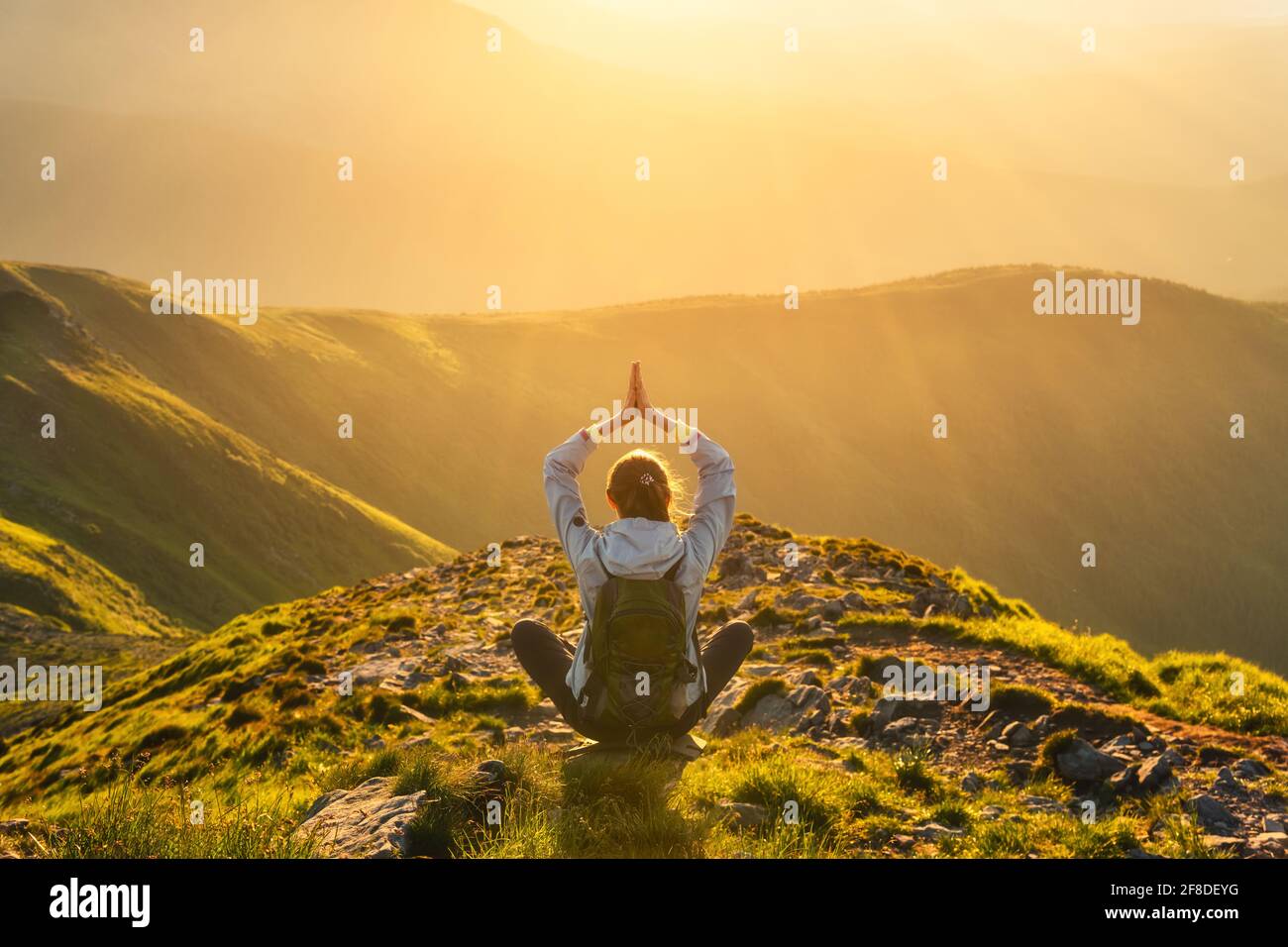 Young woman with backpack sitting on the mountain peak Stock Photo