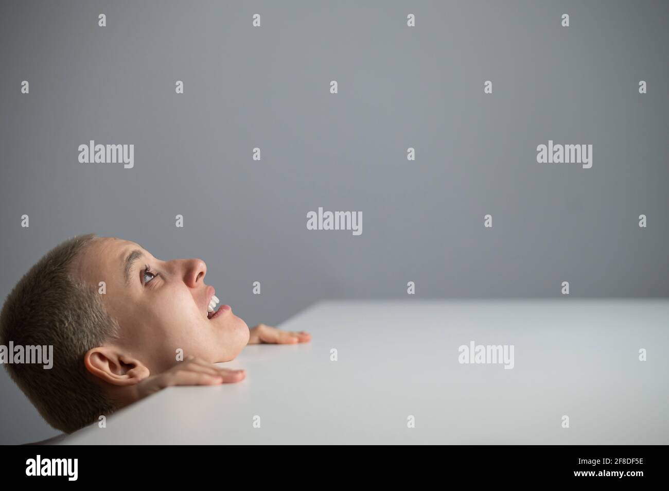 Woman with short blonde hair peeking out from under the table on a ...