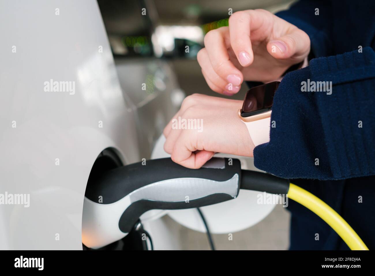 Woman uses her smart watch for opening an electric car and unplugging