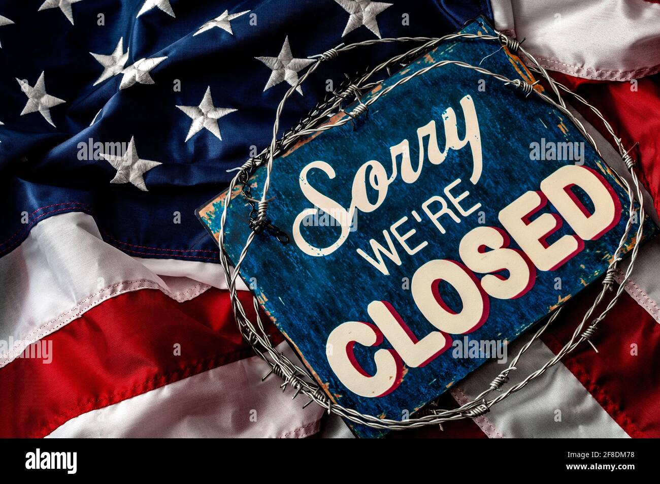 Political isolationism and economic slowdown in the United States of America concept with close up a sorry we're closed sign wrapped in barbwire on to Stock Photo