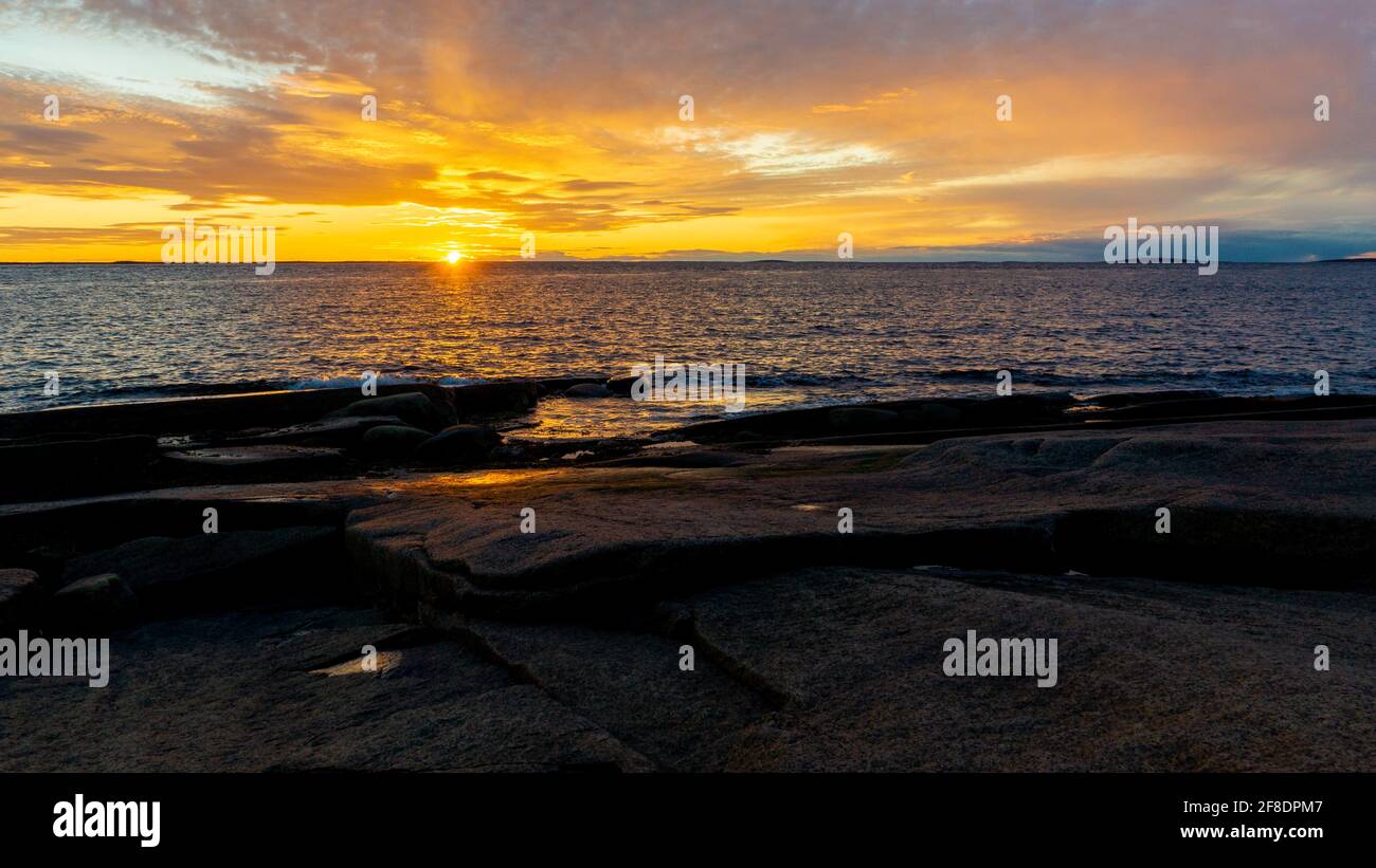 Colorful sunset on the White sea. The sun sets in the clouds. Rocky coastline. Stock Photo