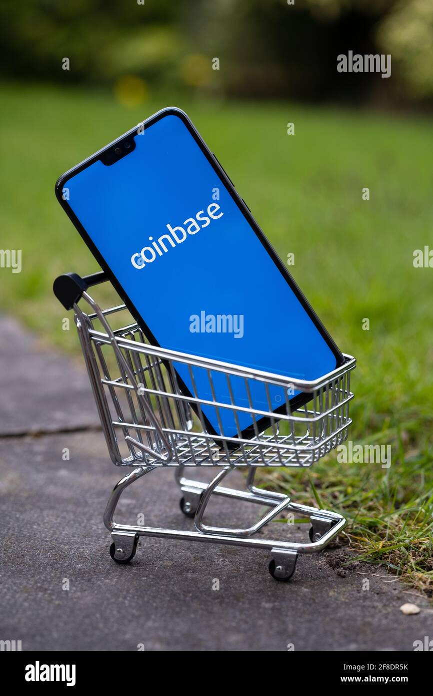 Coinbase IPO concept. Coinbase app logo seen on the screen on smartphone which is placed into miniature shopping trolley. Stafford, United Kingdom, Ap Stock Photo