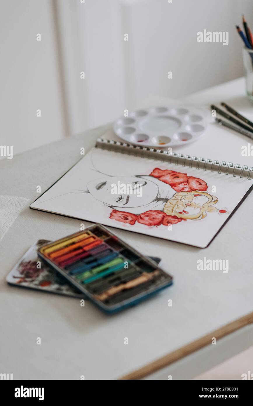 Closeup of a painting of a woman in a sketchbook on the desk Stock