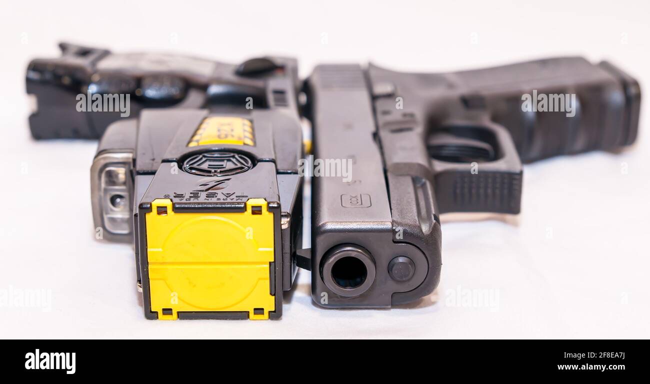 A black Glock 9mm pistol with a X26 Taser gun, both used by law enforcement and with a white background Stock Photo