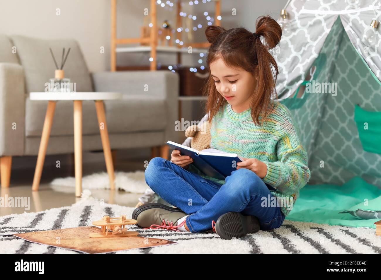 Cute little girl reading book at home Stock Photo - Alamy
