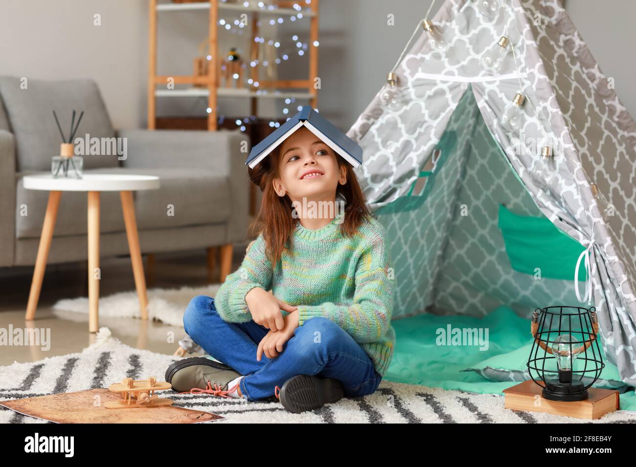 Cute little girl reading book at home Stock Photo - Alamy