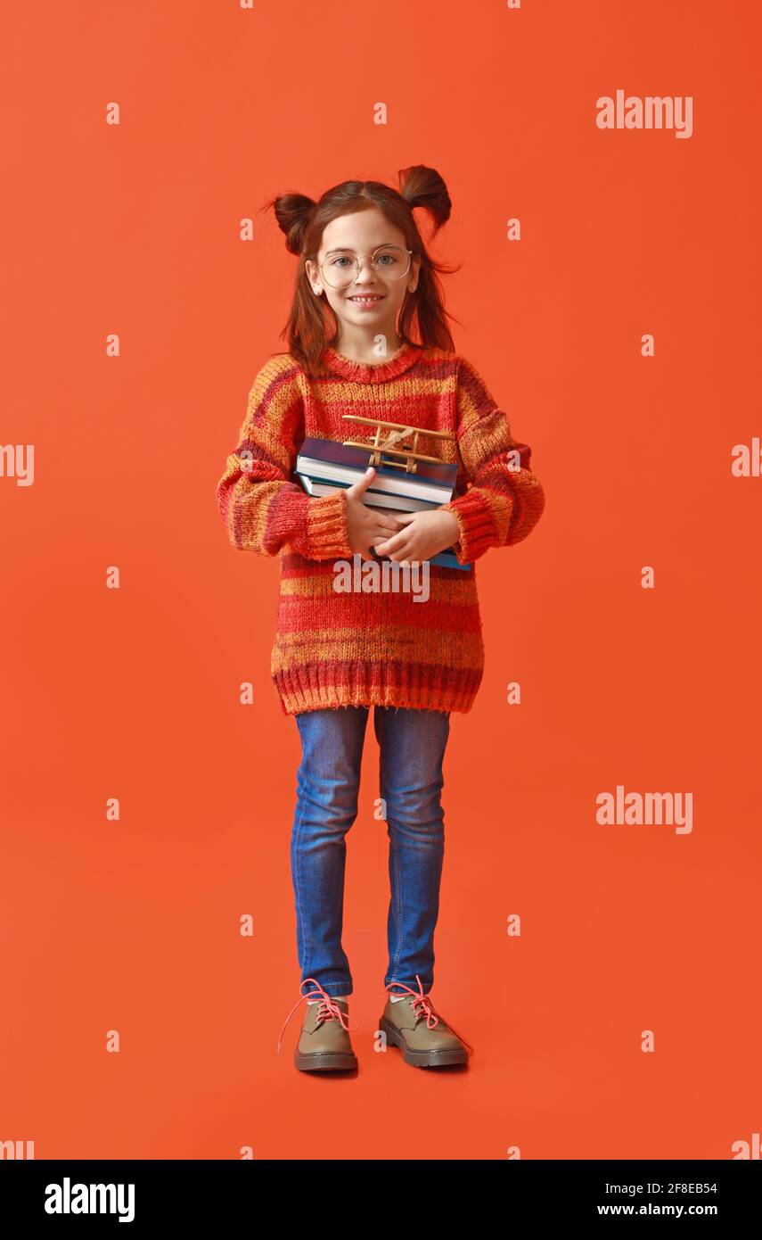 Cute little girl with books on color background Stock Photo - Alamy