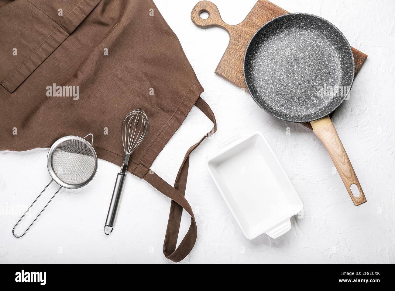Apron and set of kitchen utensils on light background Stock Photo - Alamy