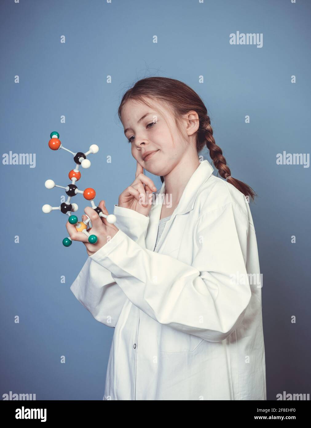 pretty girl with two braids is dressed as scientist and holds model of ...