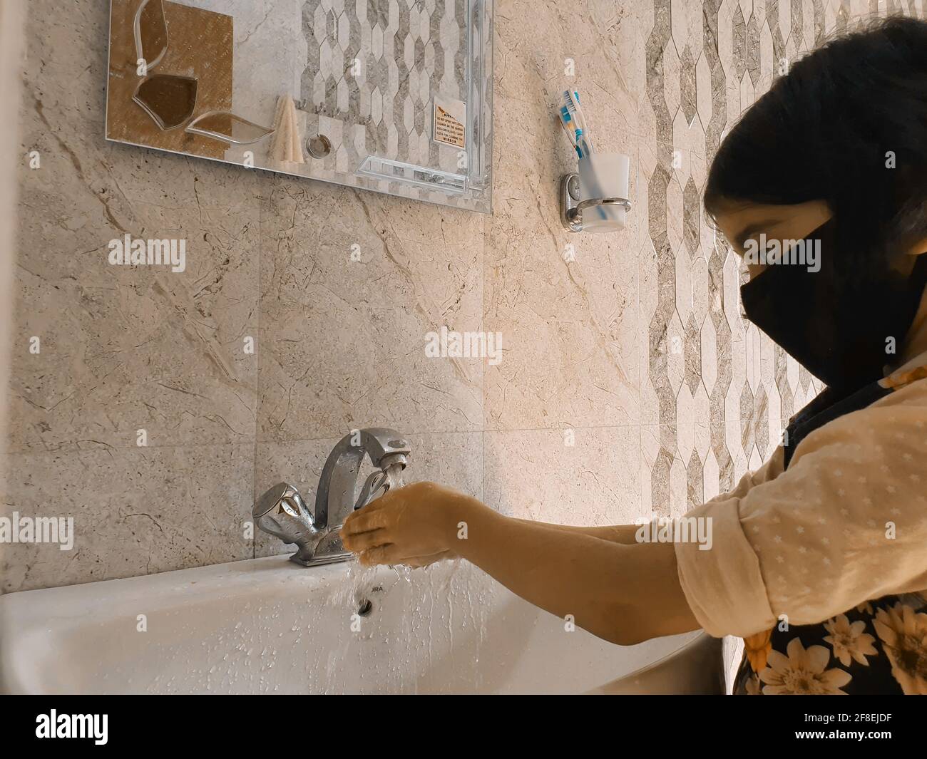 Masked Children washing hands during coronavirus pandemic. Hand wash mask wearing and using sanitiser are recommended by world health organisation. Stock Photo