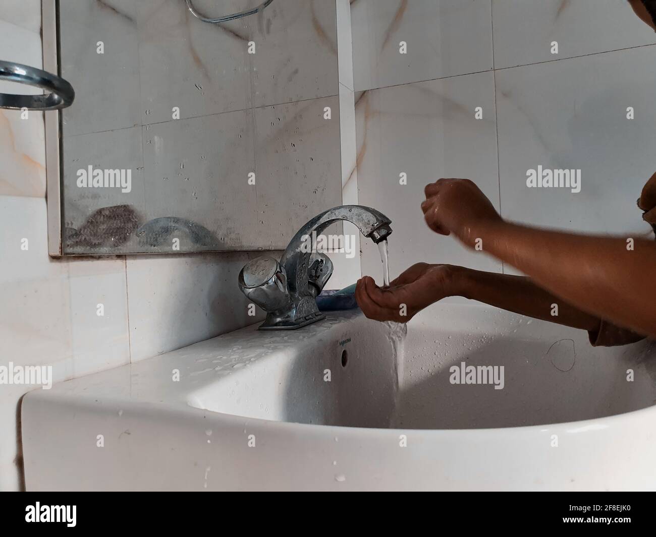 Masked Children washing hands during coronavirus pandemic. Hand wash mask wearing and using sanitiser are recommended by world health organisation. Stock Photo