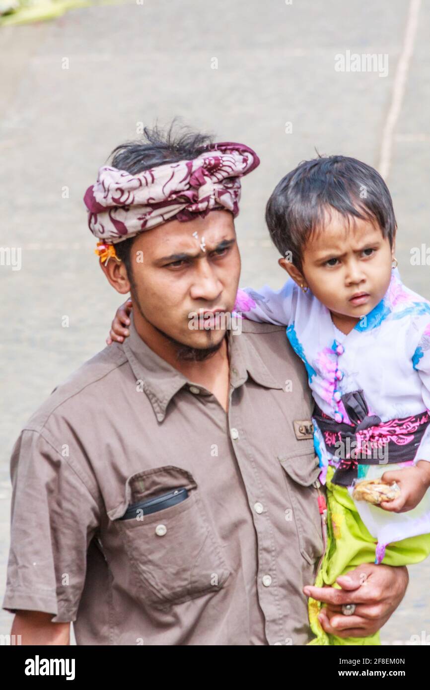 Bali, Indonesia - July 6th 2011: Balinese man with daughter going to the temple. Most Balinese follow the Hindu religion. Stock Photo