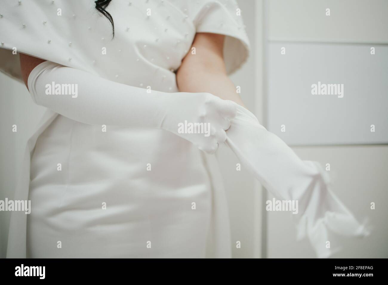 Bride getting ready for her wedding putting on her white long gloves ...