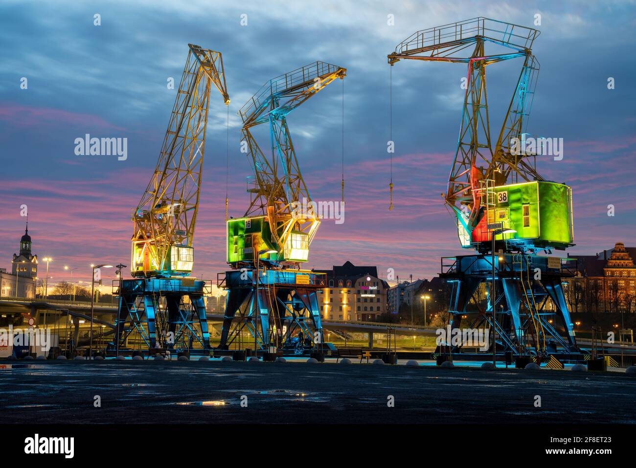 Historic port cranes in Szczecin illuminated with effective illumination against the beautiful evening sky Stock Photo