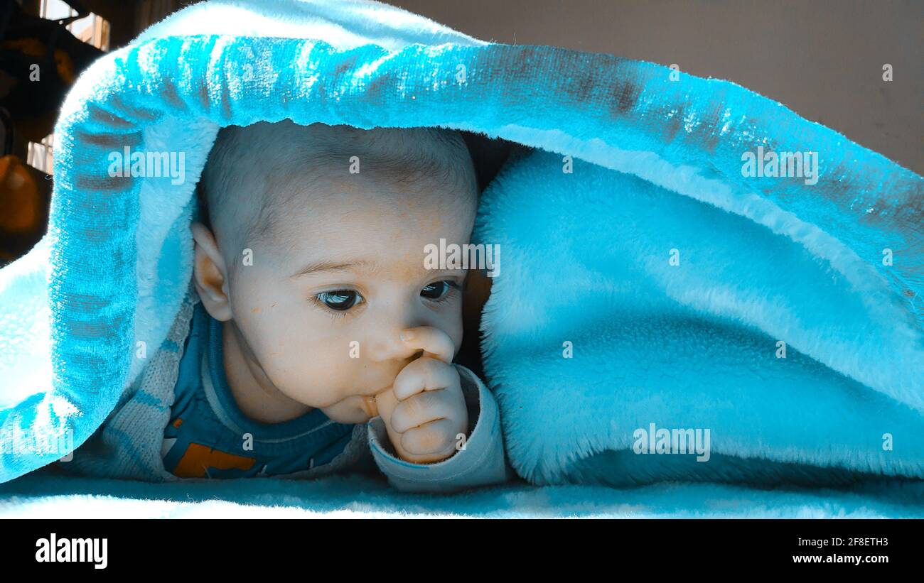 Smiling kid photographs at home under blanket looks beautiful. Digital