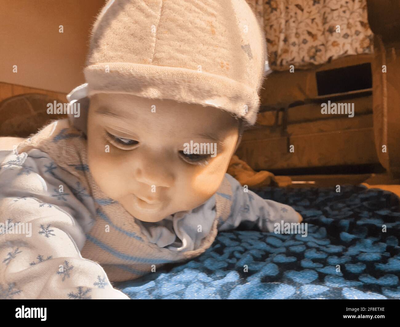 Smiling kid photographs at home under blanket looks beautiful. Digital