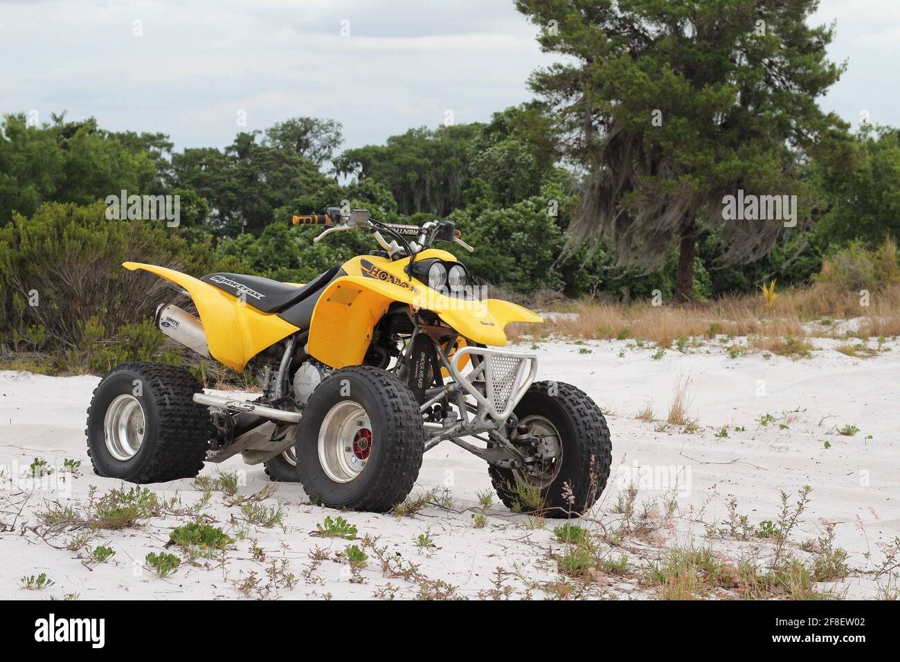 Yellow Honda ATV dirt bike outside parked on a sand hill near a mud slide read for fun. Stock Photo