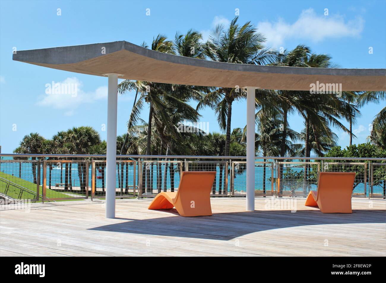 Beautiful outdoor lounge area with orange beach chairs underneath shade. Tropical paradise hotel vacation in Miami Beach Florida. Stock Photo