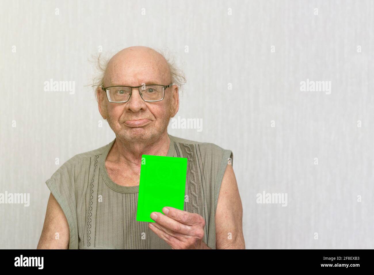 Old retired bald man with eyeglasses in gray shirt is blank in his hand. Stock Photo