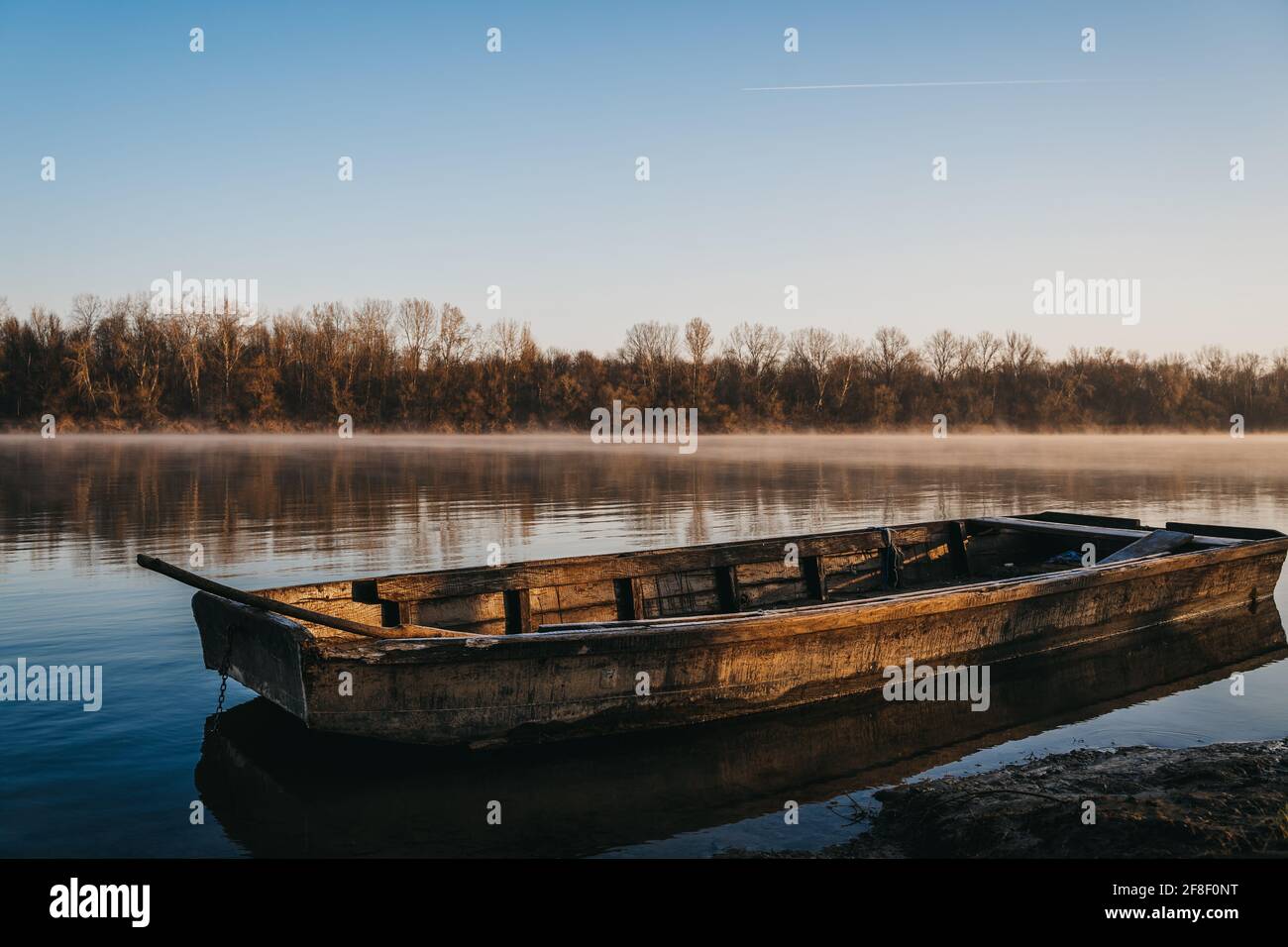 Old wooden boat on the water of a calm lake at sunrise Stock Photo - Alamy