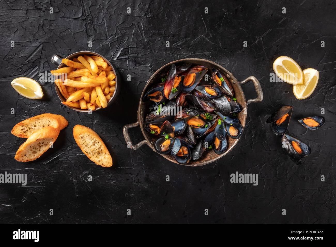 Mussels, overhead shot with French fries, lemon, and toasted bread