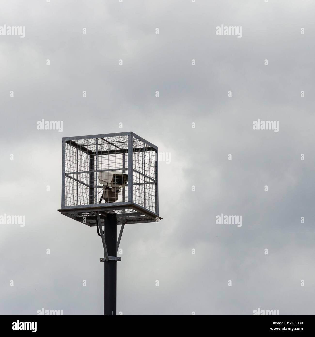 A CCTV camera inside a security cage on the top of a pole Stock Photo