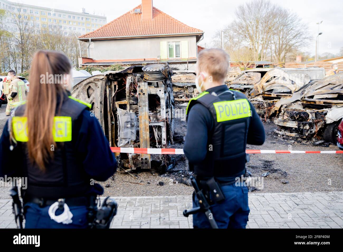 Berlin, Germany. 14th Apr, 2021. Police officers stand in front of burnt cars on the premises of a car dealership in Berlin-Köpenick. A total of 14 cars had burned, including electric vehicles. There was initially no information about the cause of the fire. Credit: Christoph Soeder/dpa/Alamy Live News Stock Photo