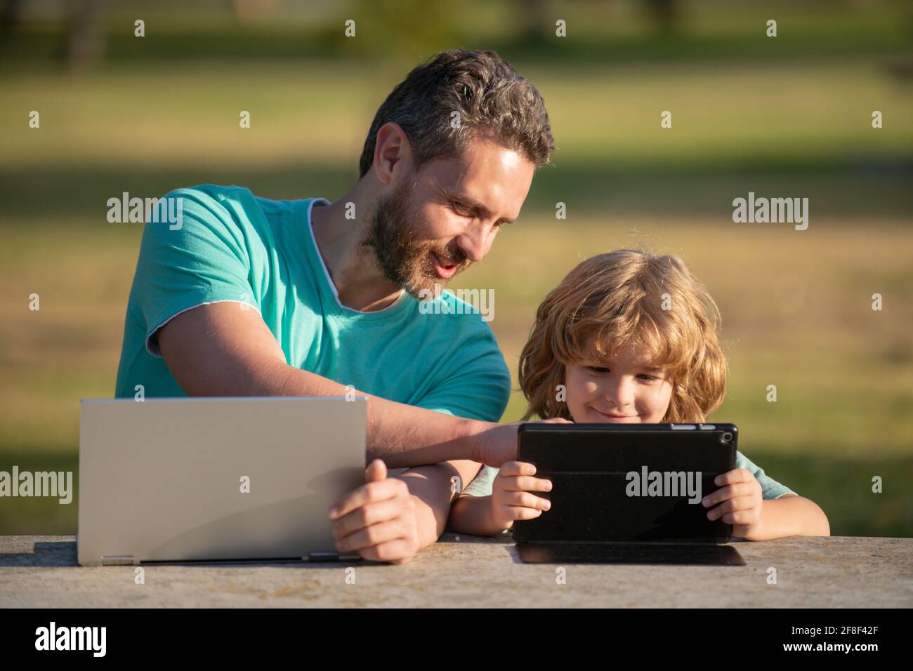 Happy father using laptop relax with schooler son holding laptop have ...
