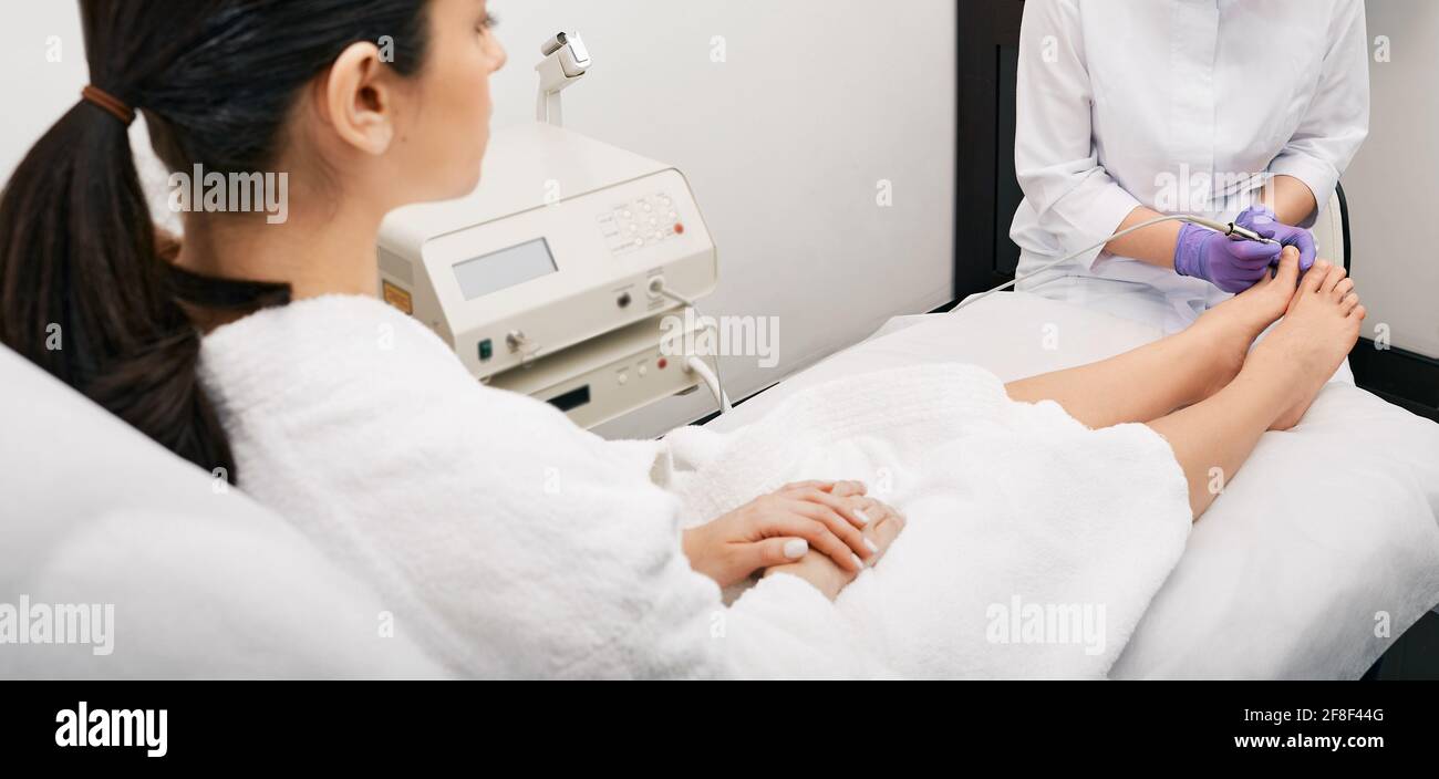 Laser treatment of onychomycosis. Woman gets laser treatment fungal infection on toenail and onychomycosis treatment with a medical laser Stock Photo
