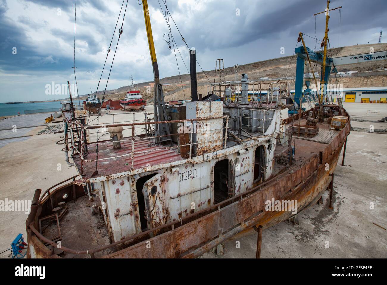 Mangystau, Kazakhstan - May 19, 2012: Old rusted ship. Bautino bay, Caspian Sea. Ship-repairing yard. Grey cloudy storm sky. Stock Photo