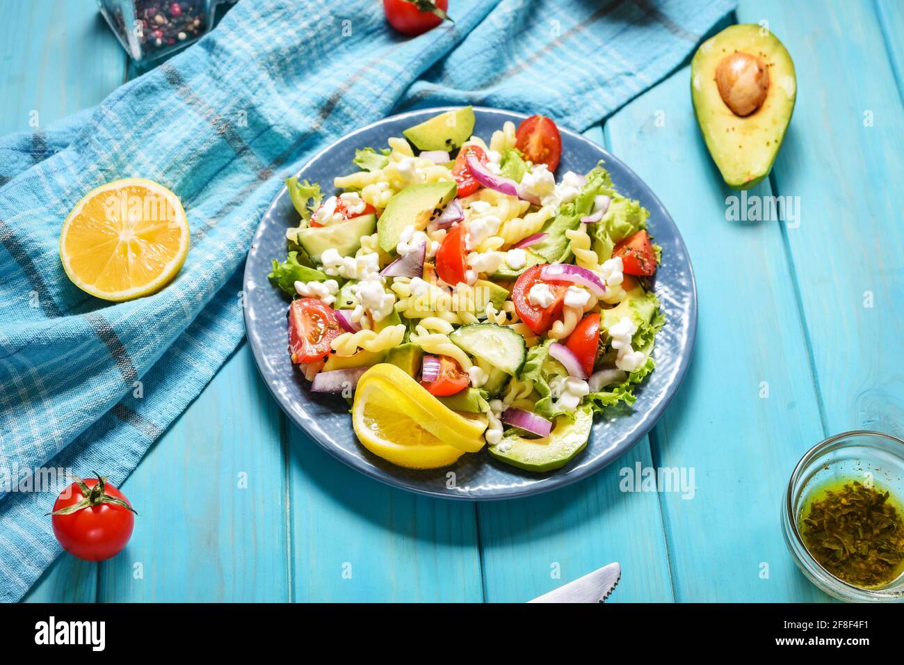 Vegetarian healthy lunch - pasta salad with fresh vegetables, avocado and feta on a blue wooden background Stock Photo