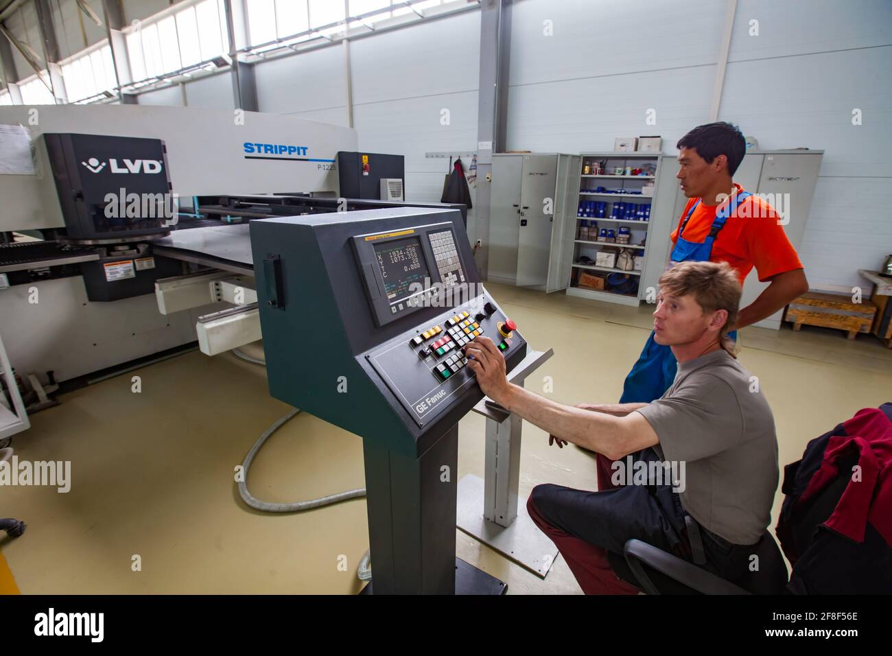 Aktau, Kazakhstan. CNC laser cutting machine and two workers with control  panel. Production of special electric equipment. RIG Ltd Stock Photo - Alamy