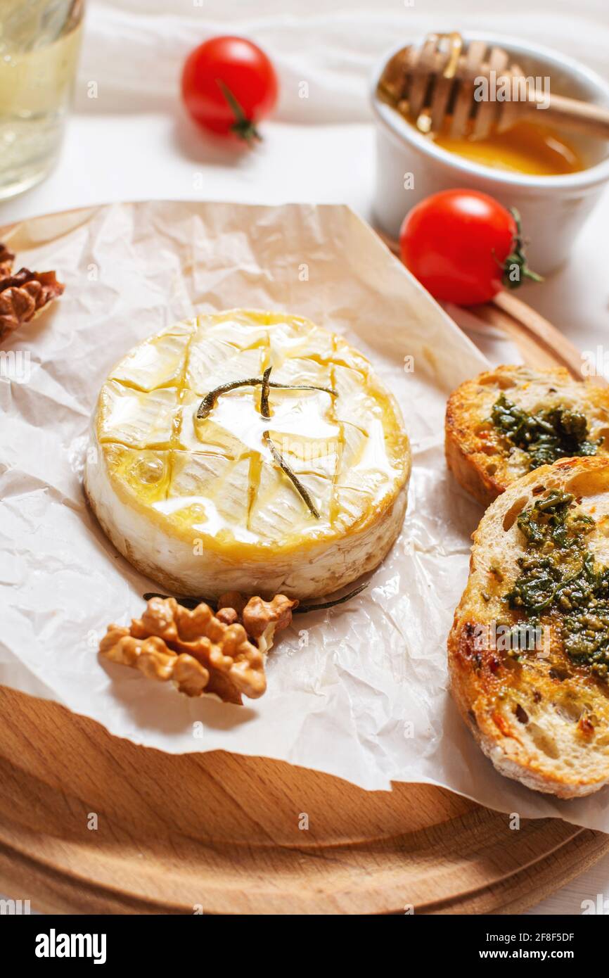 Delicious beautiful baked camembert with honey, walnuts, herbs and cranberries. Stock Photo
