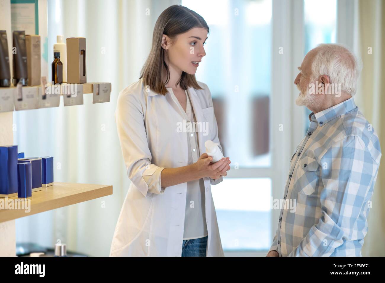 Perfumer Assistant Young shop assistant in perfume shop showing a new fragrance to a ...