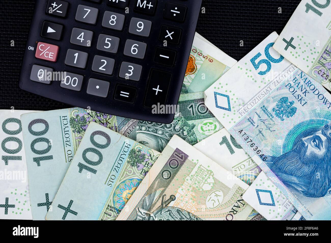 Calculator and Polish banknotes of PLN 100 and PLN 50 on a black  background. Photo taken under soft artificial light Stock Photo - Alamy