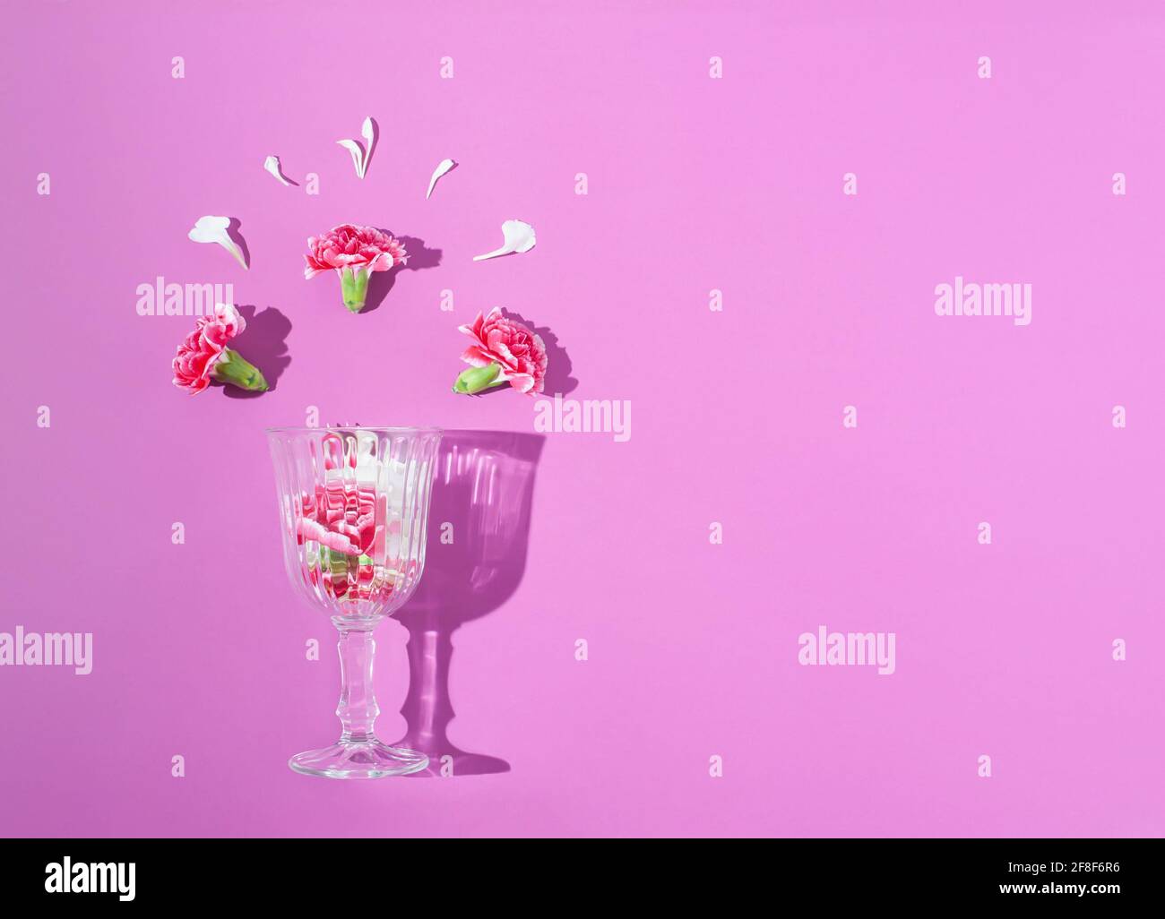 Spring colorful flowers in a wine glass on bright lilac background. Minimal spring concept. Nature background idea. Stock Photo