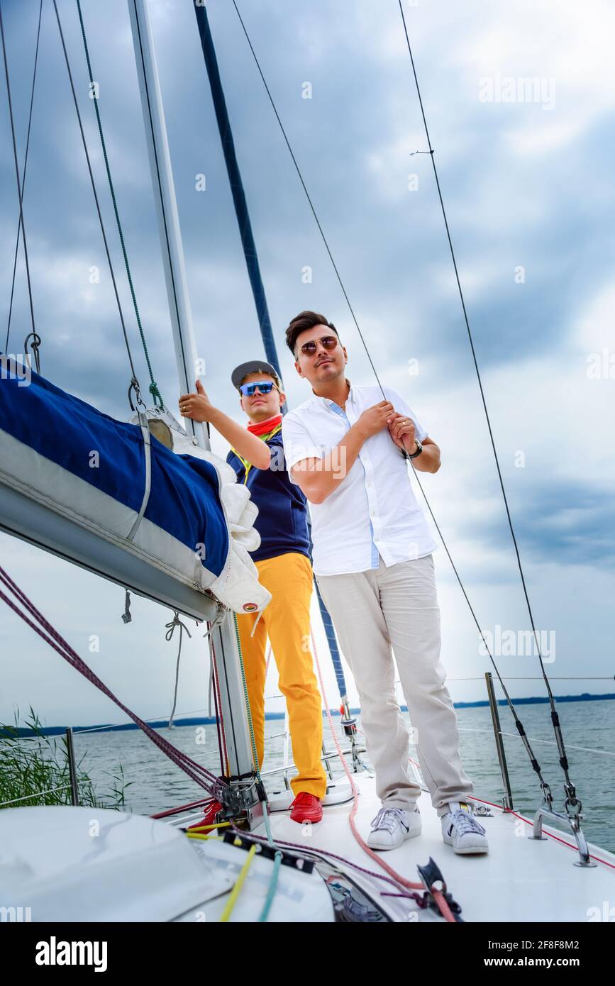 two young man standing on a sailboat. Summer vacations, cruise