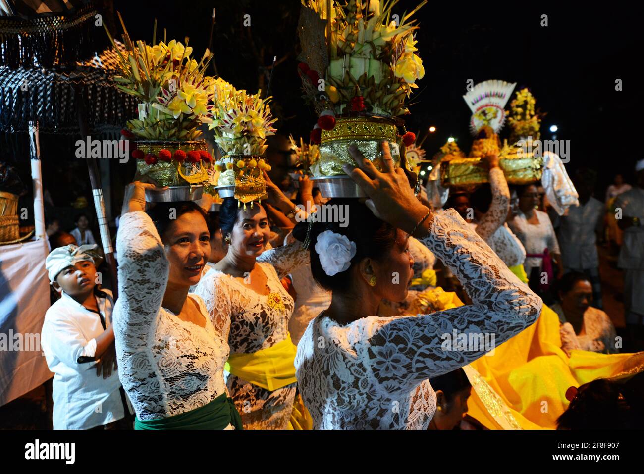 Balinese women carrying temple offerings on their head during a