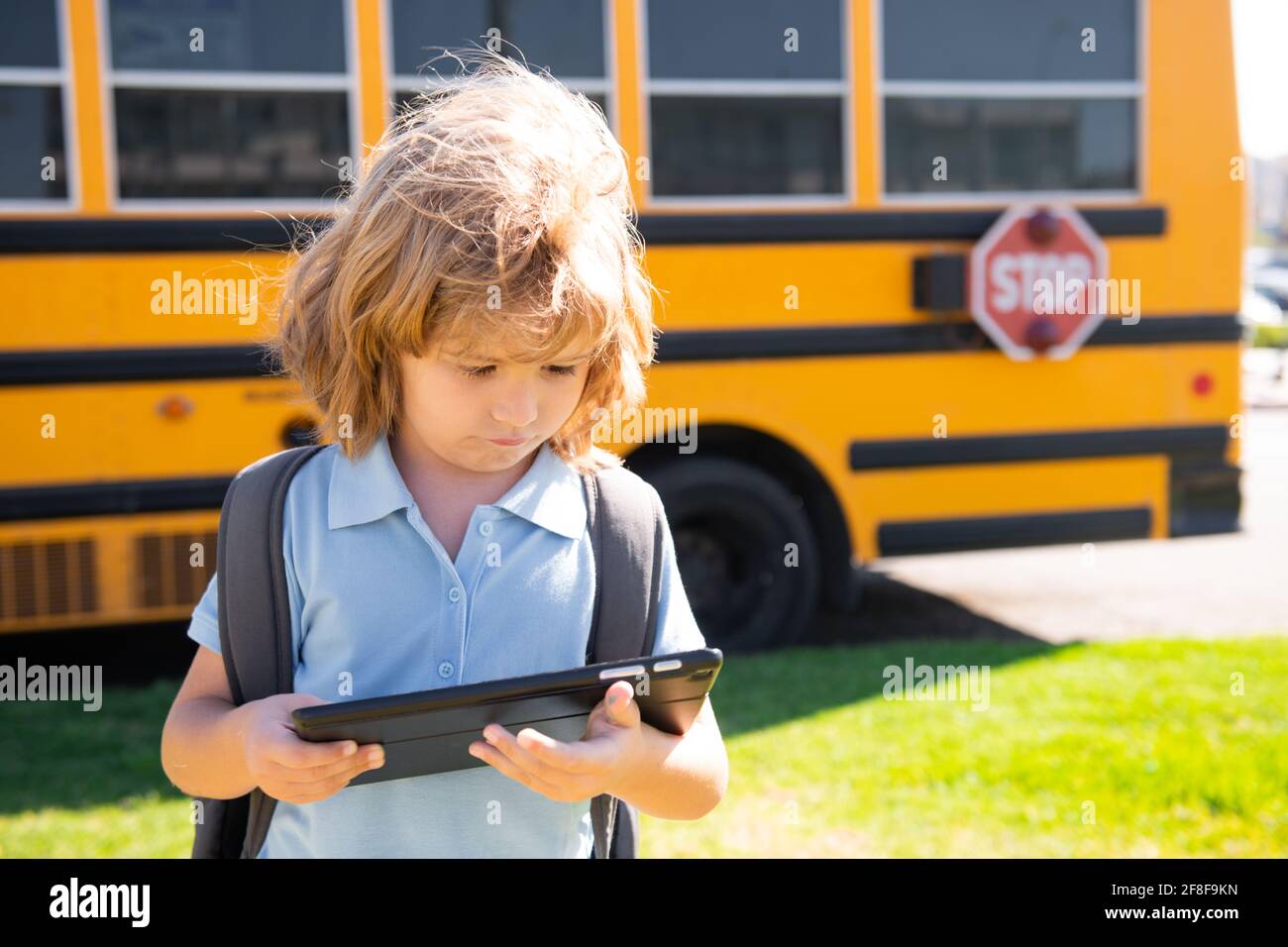 Child does school homework with tablet in the park near school bus ...