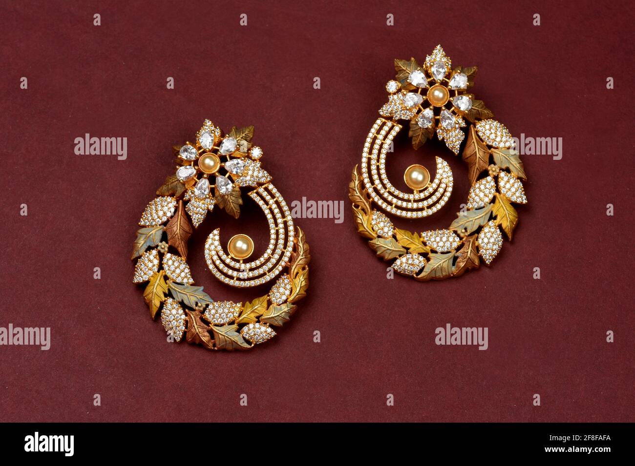 Glamorous antique Golden pair of earrings on red background Indian traditional jewellery, Bridal Gold earrings wedding jewellery, Vintage earring Stock Photo