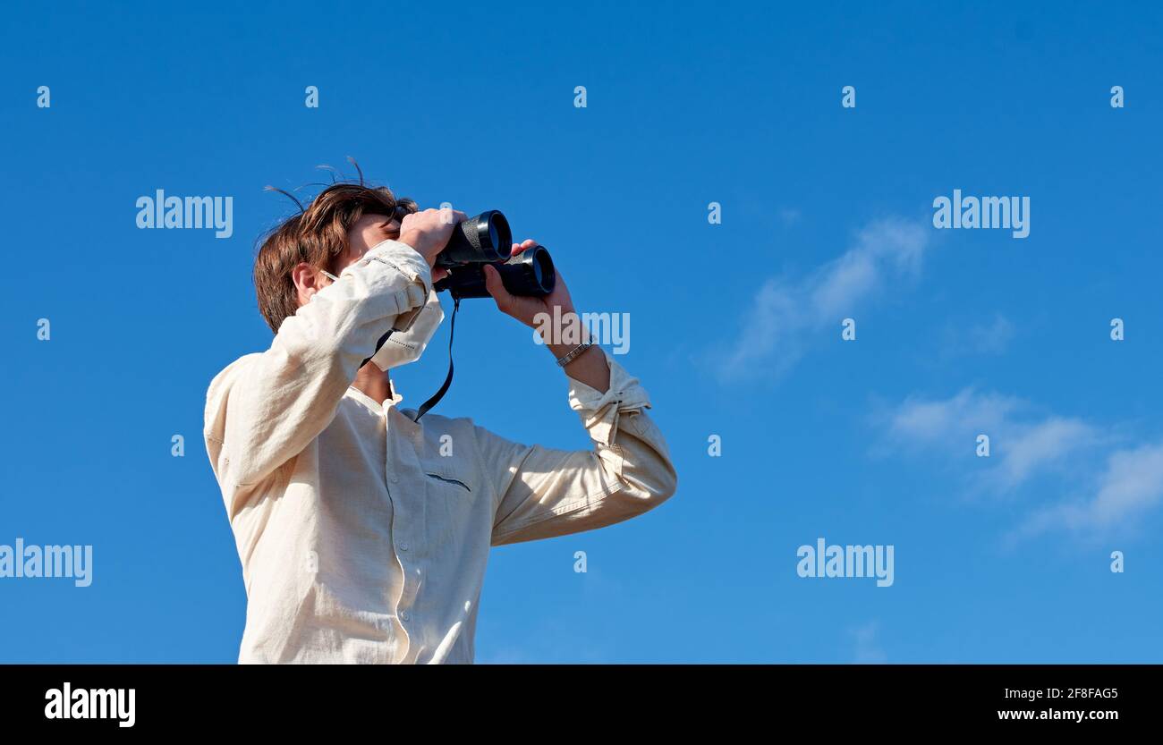 Spanish adventurous male traveler wearing a mask using binoculars and