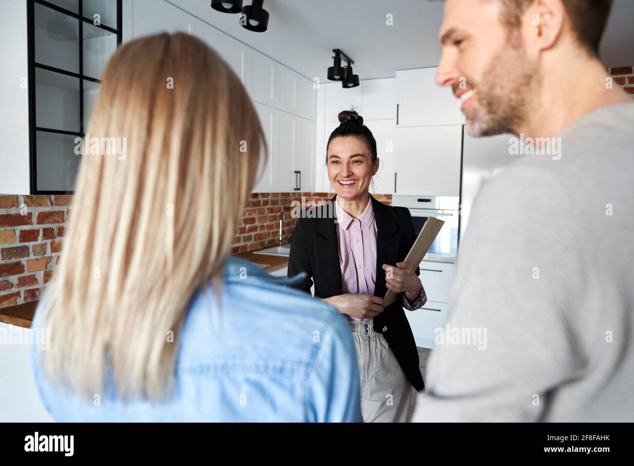 Happy real estate agent showing new apartment to a couple Stock Photo