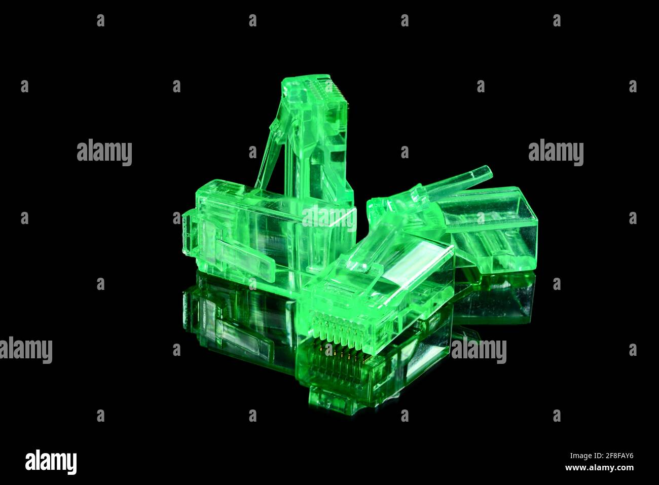 Connector rj-45. Four neon green transparent connectors rj45 for network and internet. Close up macro isolated on black background with reflection. Stock Photo