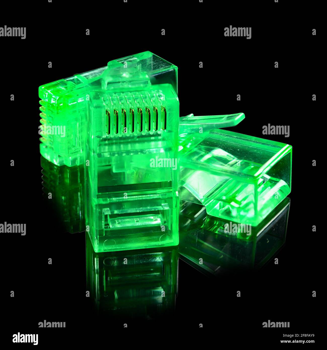 Connector rj-45. Three neon green transparent connectors rj45 for network and internet. Close up macro isolated on black background with reflection. Stock Photo