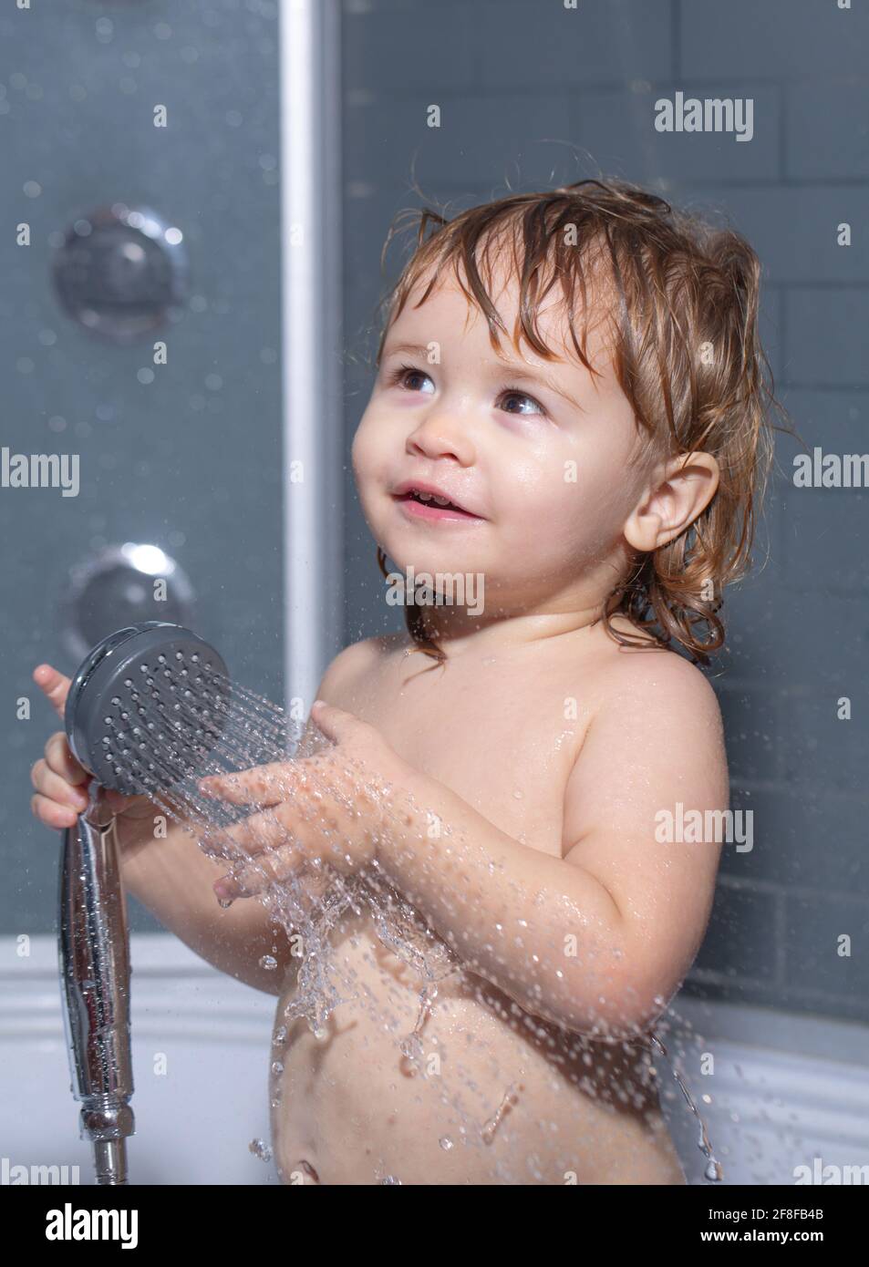 Child bathing under a shower. Bathing baby. Happy kid with soap foam on