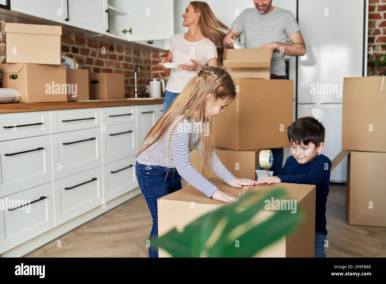 Siblings help with packing cardboard boxes for moving house Stock Photo