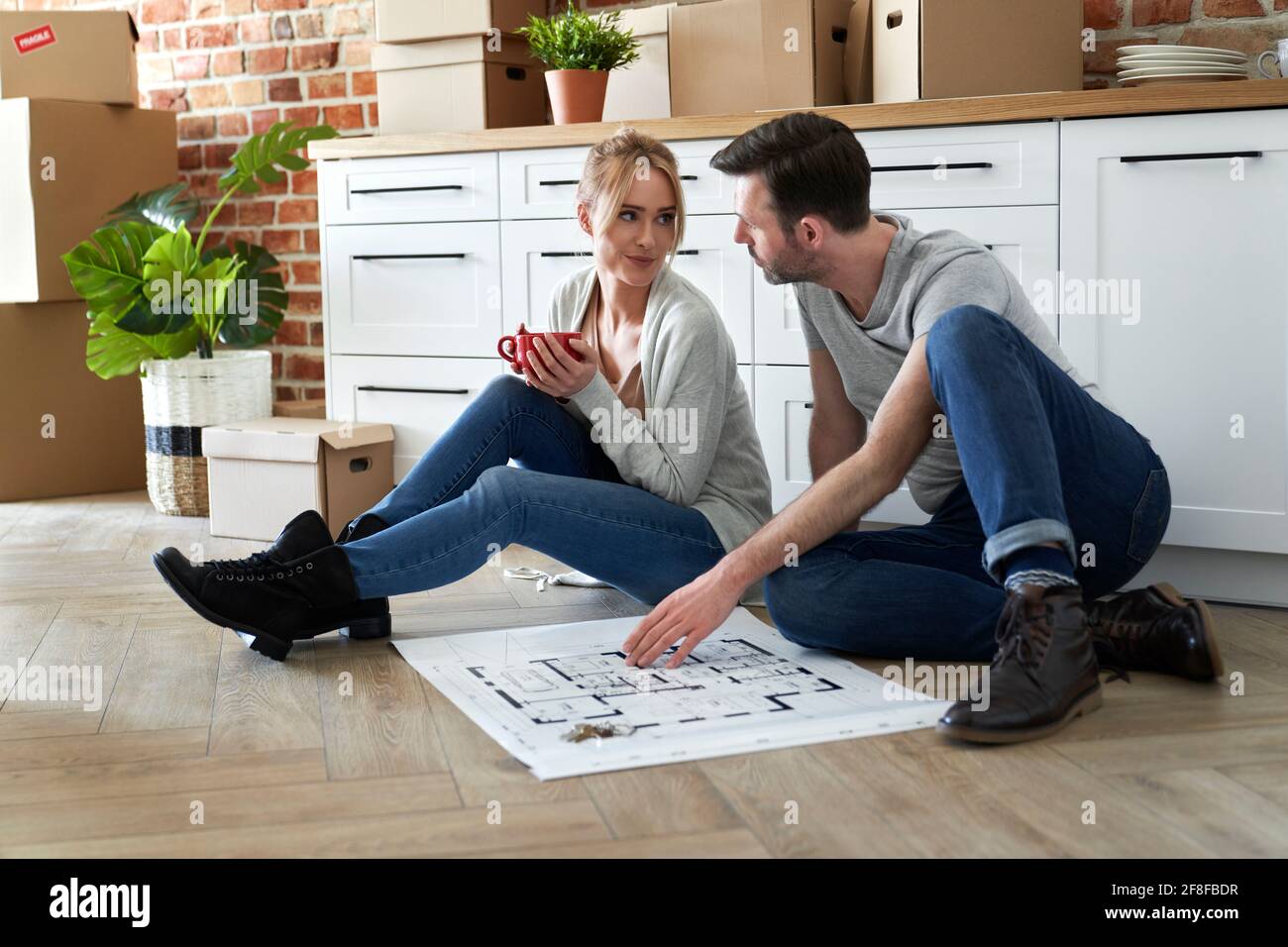 Couple sitting on the floor in their new apartment Stock Photo